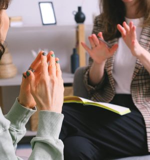 Crop unrecognizable female psychologist and patient discussing mental problems during session